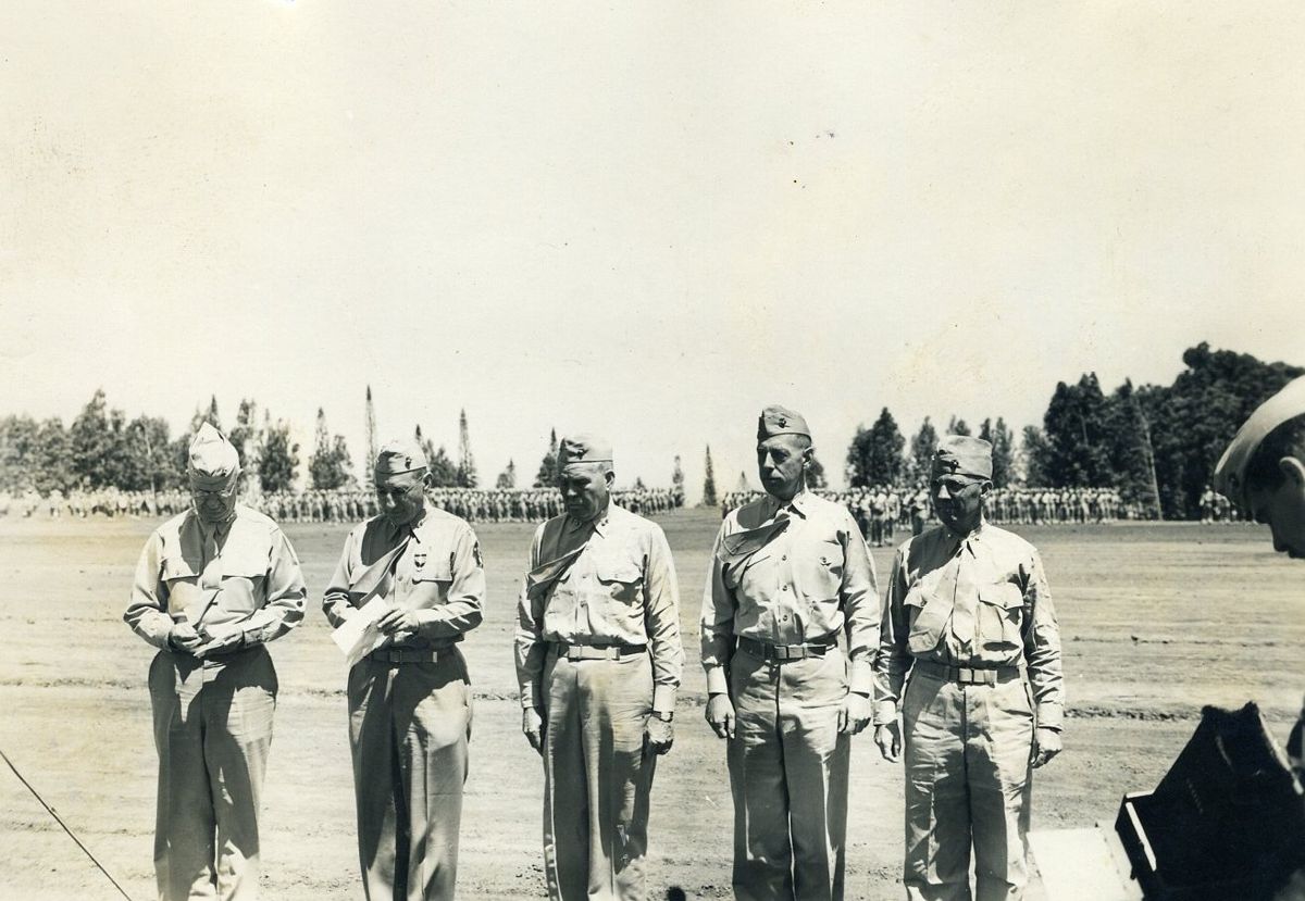 Five Marine officers in khakis standing in a line on an open field, hills and eucalyptus trees in the distance