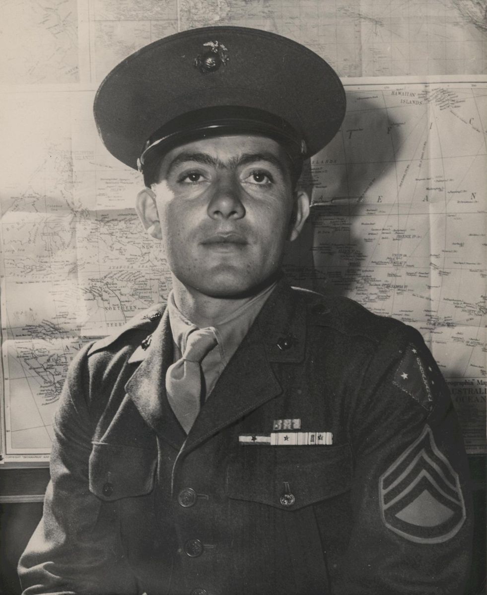 A portrait of a Marine sergeant in a service uniform and peaked cap, sergeant stripes on his sleeve and ribbons on his chest