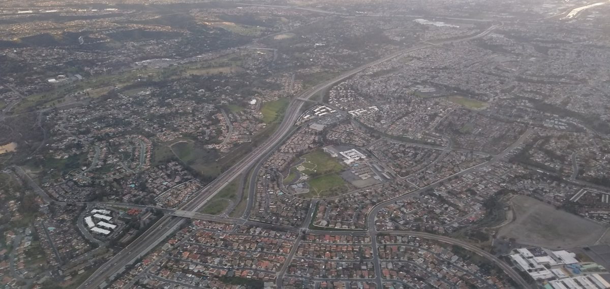 An aerial view of a freeway running through dense neighborhoods and hills