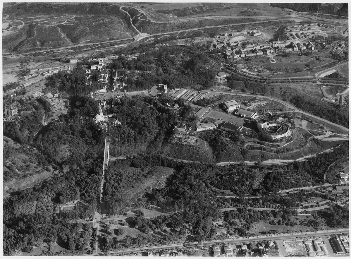 An aerial photograph of a large wooded park on a mesa cut by canyons, clusters of buildings and roads across it