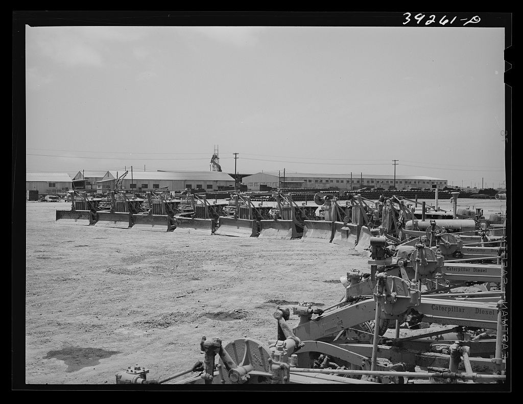 Heavy road equipment in the foreground and rows of new two story buildings going up on a flat mesa
