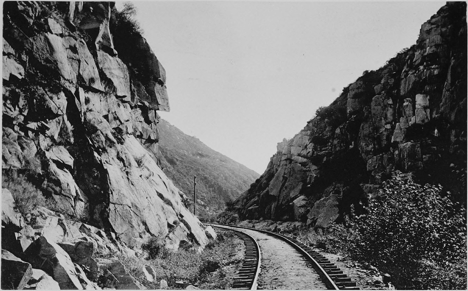 A railway track running between high broken rock walls in a narrow canyon
