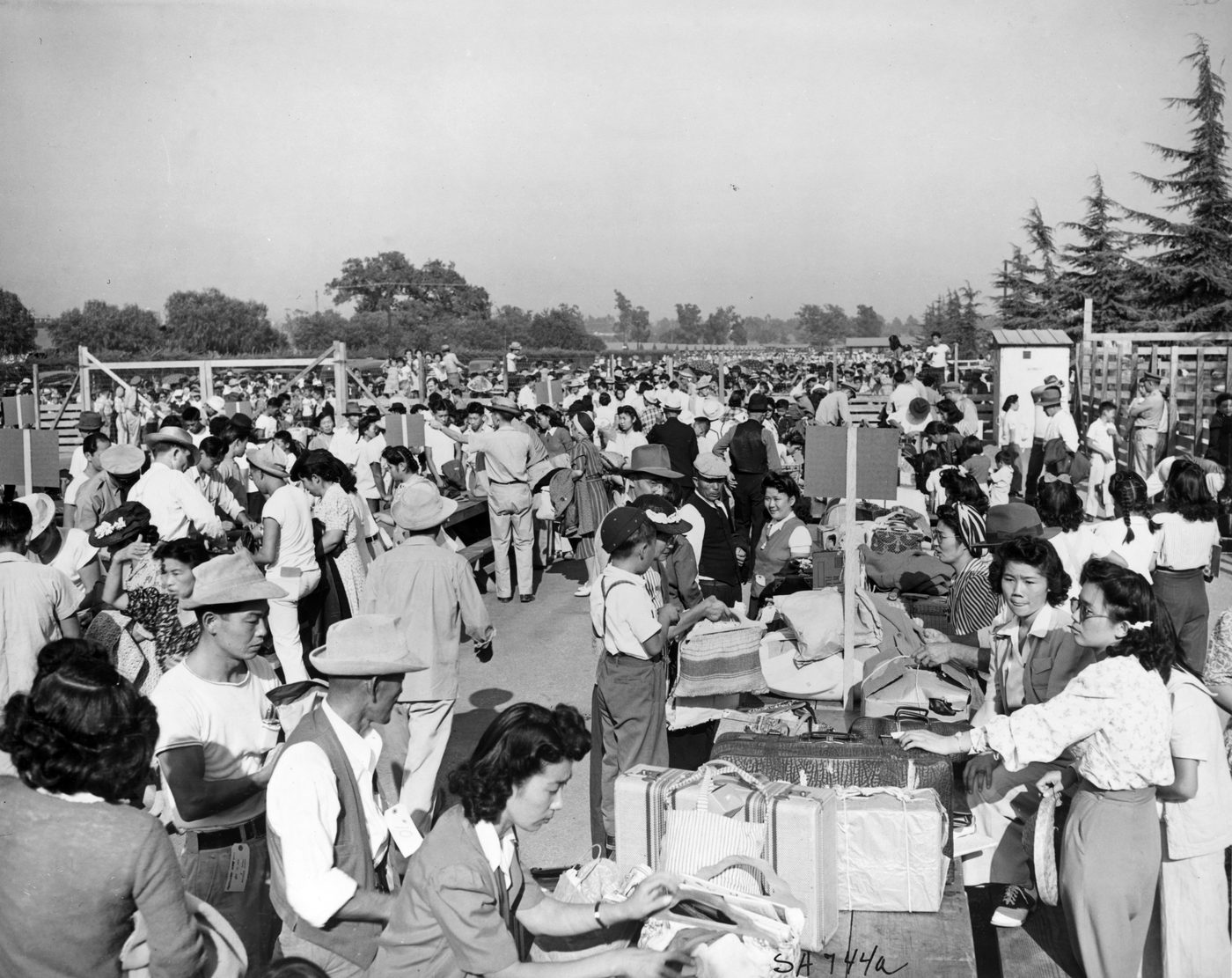 Japanese American families identifying hand baggage before being moved out of the assembly center at Santa Anita, California, 1942