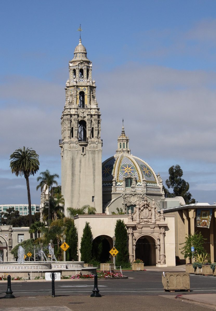 An ornate Spanish Colonial tower and tiled dome rising above palm trees in Balboa Park