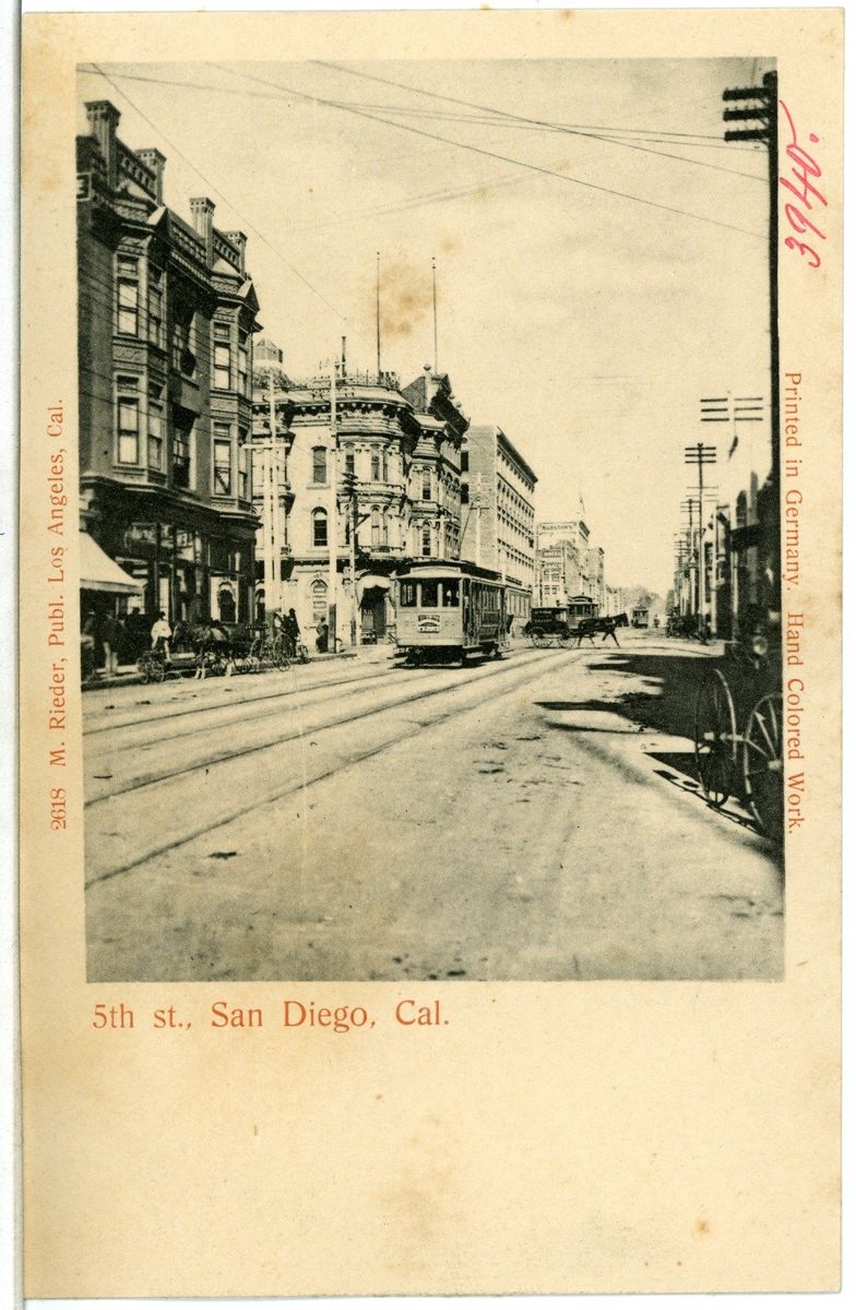 A tinted postcard of a downtown street with a streetcar, storefront awnings and brick commercial buildings