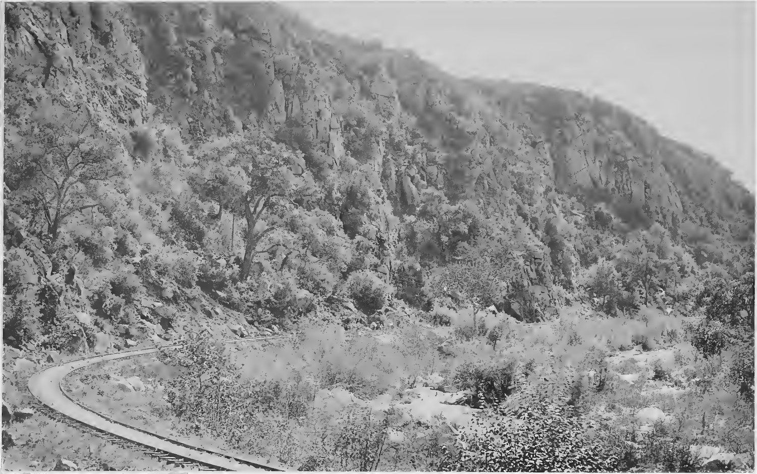 The California Southern Railroad track curving around the base of a steep brush covered canyon wall in Temecula Canyon, photographed in 1887