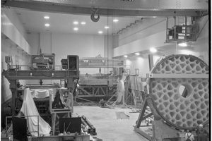The 200-inch Pyrex telescope disk standing on edge in the Caltech optical shop in Pasadena in 1936, its back face cut into a deep honeycomb of ribs, with two men standing at its base for scale