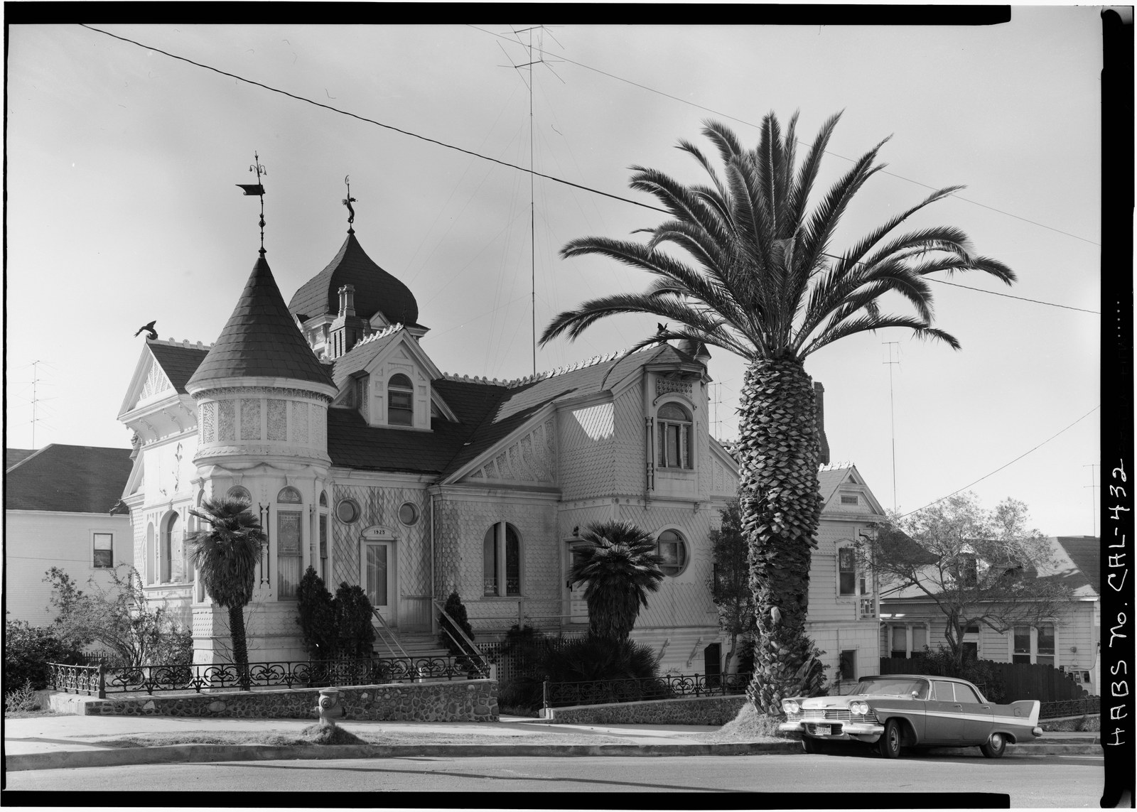 Villa Montezuma at 1925 K Street in San Diego, a Victorian house with an onion dome, a corner turret and patterned shingle walls, photographed in 1964 with palms in the yard and a late 1950s car at the curb